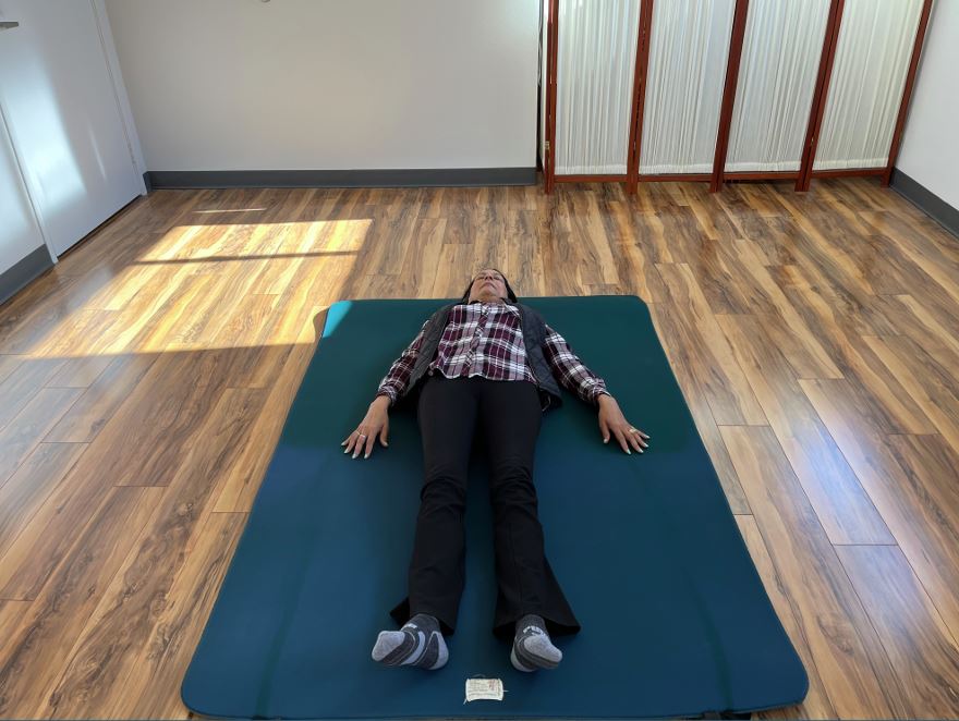 A student lying on the ground, with their arms down along the sides of their body