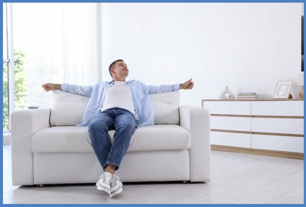 A man on a couch, arms outstretched, looking to the side