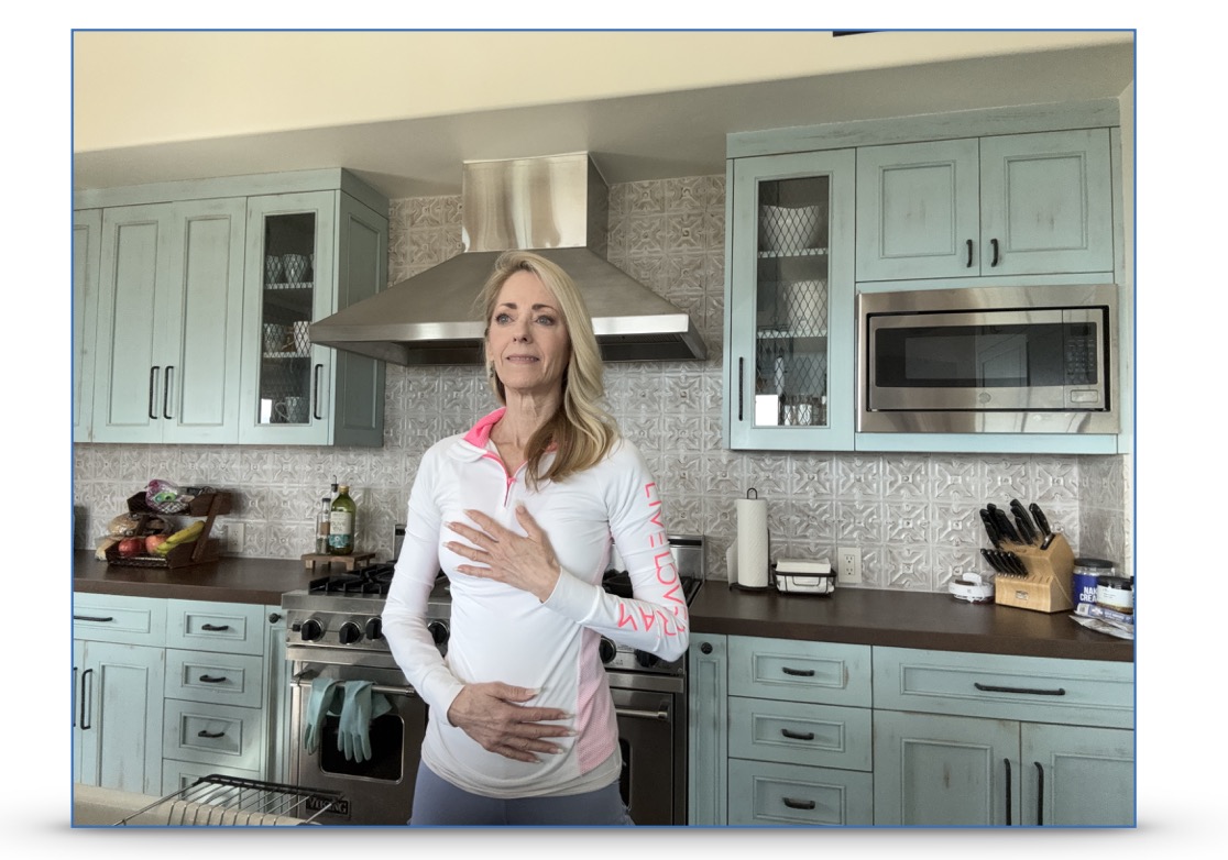 A woman placing a hand on heart and a hand on her abdomen