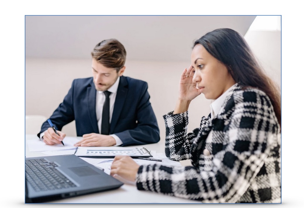 A woman holds her head and looks worried in a corporate environment