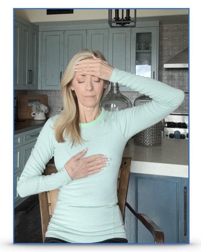 A woman standing, one hand on her forehead and one hand on her abdomen